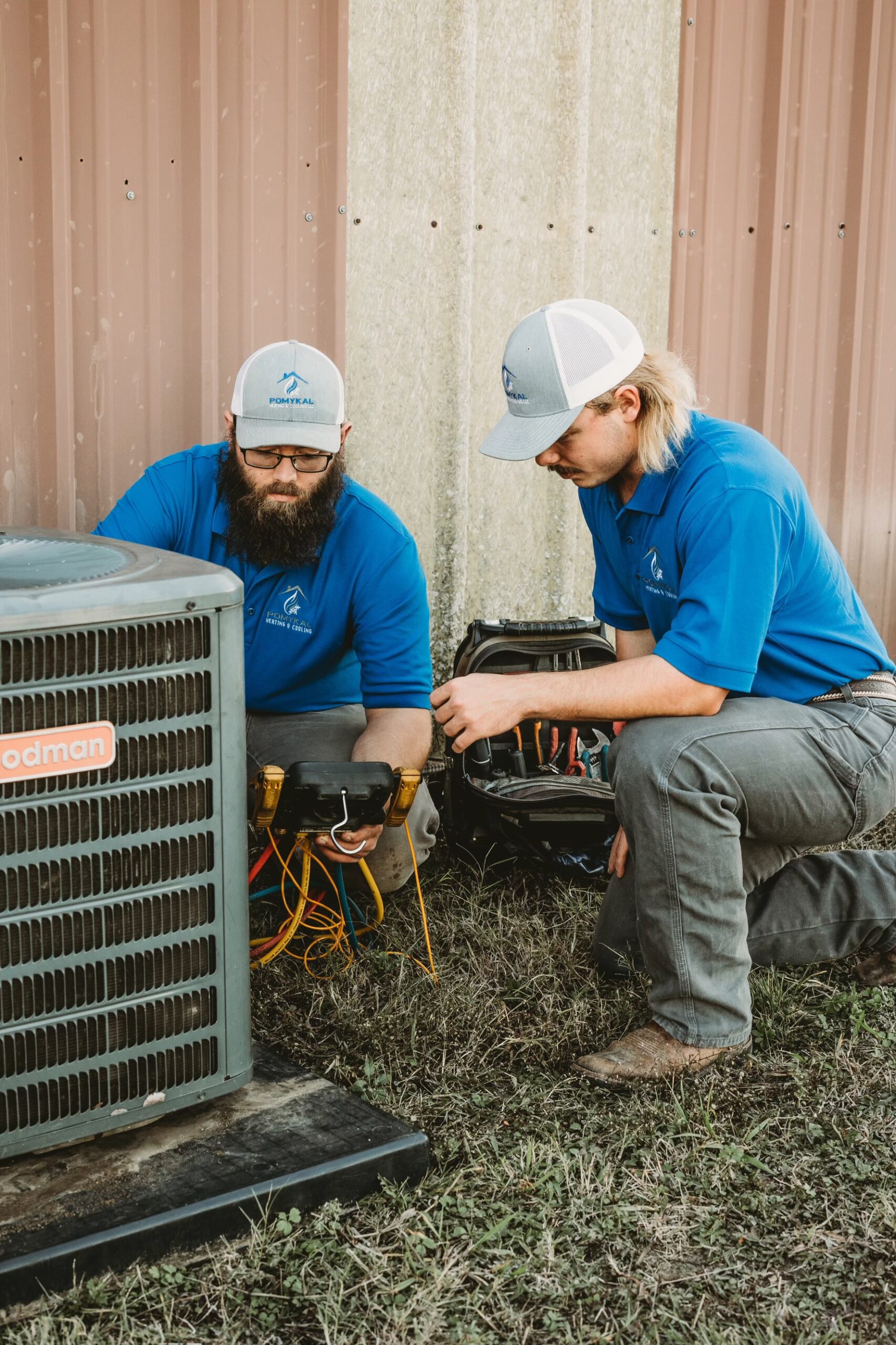 A technician from Pomykal Heating and Cooling working on an Air Conditioner.